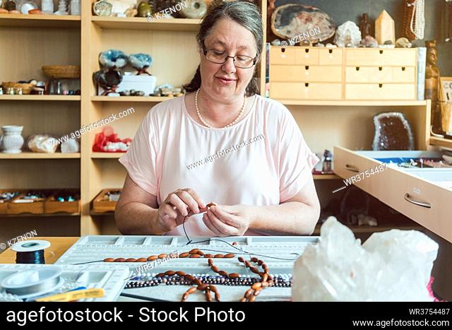Woman working on a gemstone necklace as a hobby in the workshop