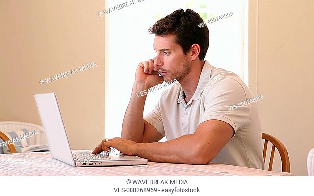 Man using laptop while speaking on phone