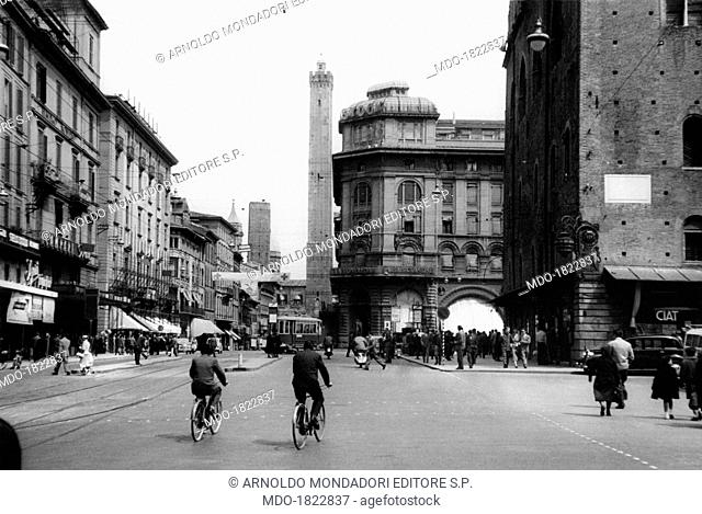 People walking on via Rizzoli. In the background the towers Garisenda and Asinelli, and the church of Saint Bartholomew and Saint Cajetan