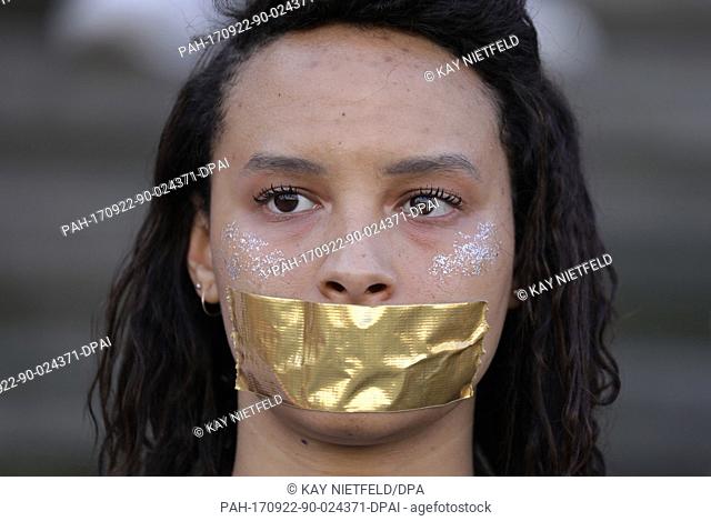 A students pasted a golden piece of paper in front of her mouth during a protest action for more democracy before a campaign event on the German federal...