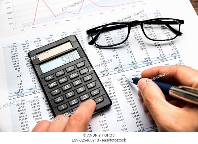 Close-up Of Businessman's Hand Calculating Financial Sheet Using Calculator