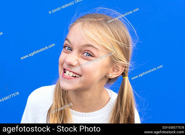 Cute young girl making funny face over blue background. Copy space. High quality photo