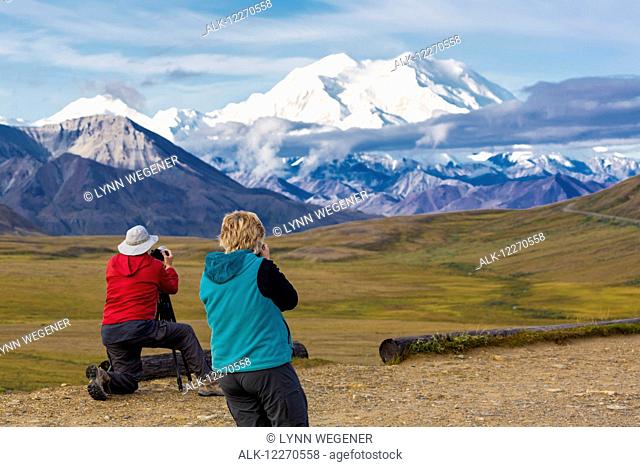 Two tourists photograph Mt. McKinley and Thorofare Pass from Stony Dome in Denali National Park, Interior Alaska, Summer, USA