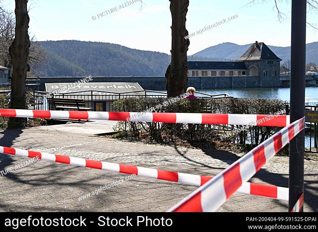 04 April 2020, Hessen, Hemfurth: Barrier tape on playground equipment is stretched in front of the Edersee barrier wall. Despite sunshine