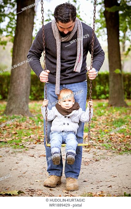 Father pushing son on a swing, Osijek, Croatia