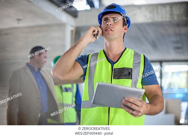 Man with cell phone and tablet on construction site