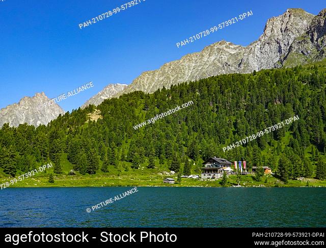 19 July 2021, Austria, Sankt Jakob: The Obersee lake with the Obersee Alpine Inn in the Hohe Tauern National Park on the Staller Sattel pass (Passo Stalle) on...