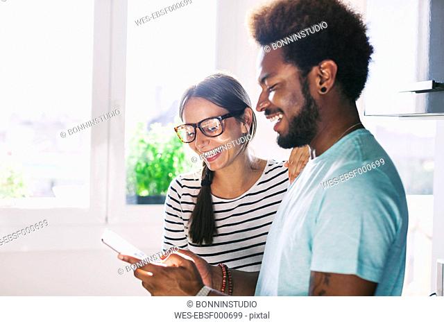 Happy young couple with phablet in their kitchen