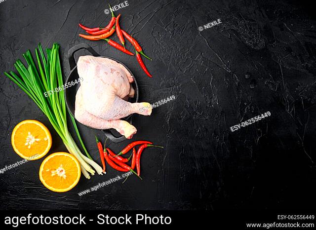 Sticky hoisin chicken ingredients set, with orange and chili, on frying cast iron pan, on black stone background, top view flat lay, with copy space for text
