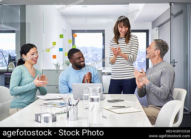 Colleagues applauding on video conference in office meeting