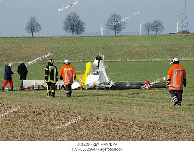 Fire fighters and workers with the German Federal Bureau of Aircraft Accident Investigation (BFU) stand by small aircraft that is lying on a field after a crash...