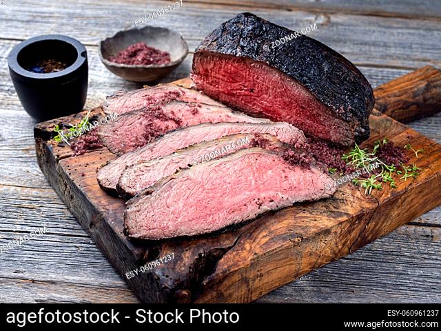 Traditional Commonwealth Sunday roast with sliced cold cuts roast beef with herbs and salt served as close-up on an old rustic wooden board