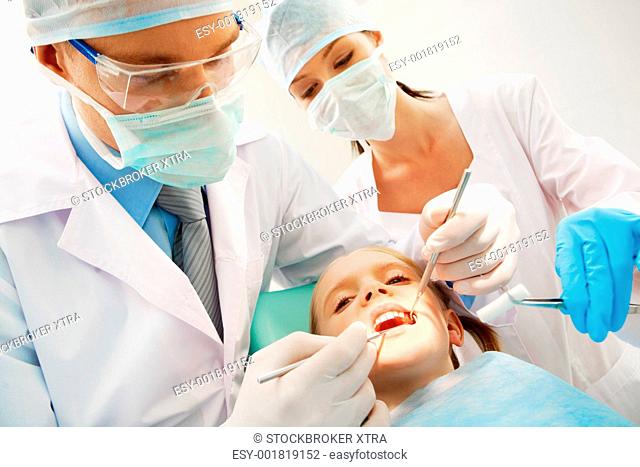 A dentist and a nurse curing little girlâ€™s teeth
