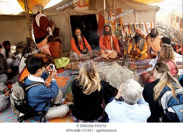 Sadhus from the Juna Akadha sit with their disciples most of them foreigners at their camp during the Ardh Kumbh Mela , , , India