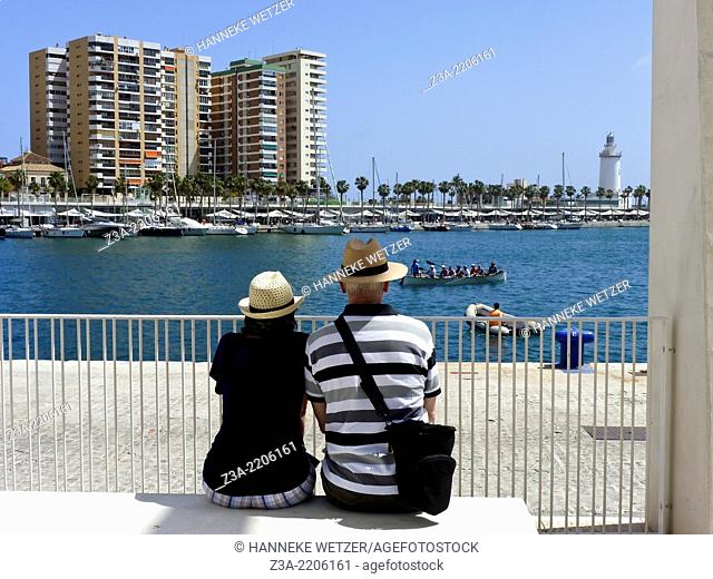 Older couple looking over the sea, sitting at a bench at the new port of Malaga, El Palmeral de las Sorpresas, Costa del Sol, Spain, Europe