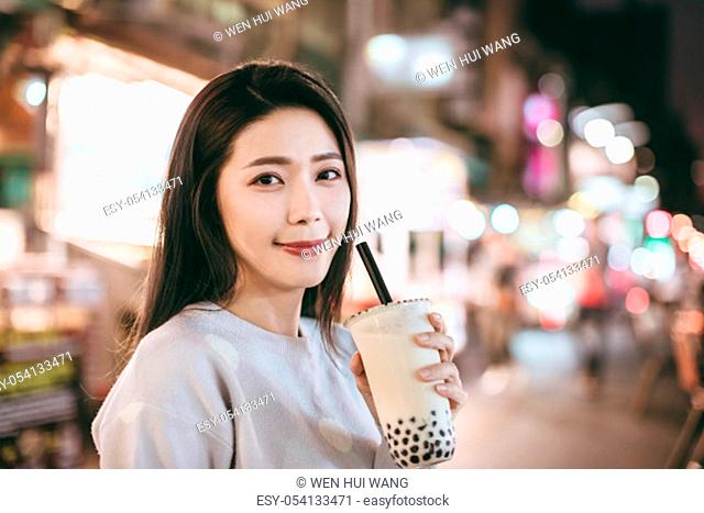 Asian woman enjoy bubble milk tea with street food in Night Market