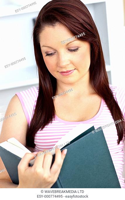 Concentrated woman reading a book at home in the living-room