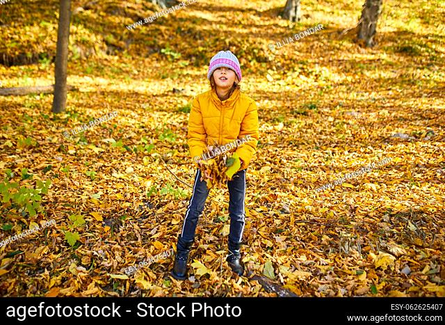 Happy adorable child girl laughing and playing yellow fallen leaves in autumn outdoors, Happy moment