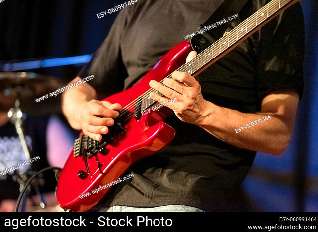 Man lead guitarist playing electrical guitar on concert stage