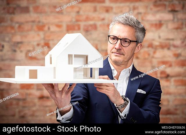Mature businessman planning while looking at model house at work place