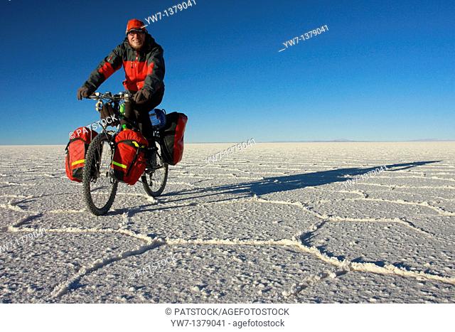 A biker is cycling through the frozen salt lake called 'Salar de Uyuni' in Bolivia