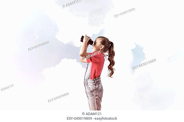 Little cute girl in overalls against sky background dreaming about future