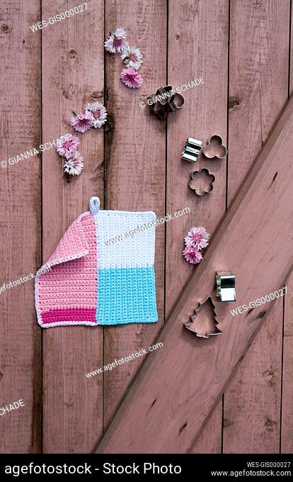 Crocheted potholder, blossoms and cookie cutters on wood