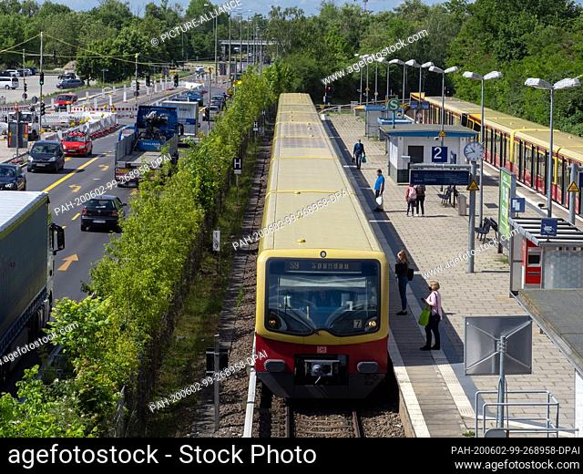 28 May 2020, Berlin: The S-Bahn S9 to Spandau stops at Altglienicke station. On the left, cars and trucks drive on a narrowed two-lane road due to the...