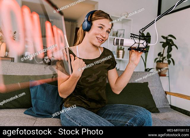 Teenage girl speaking on microphone while broadcasting at home