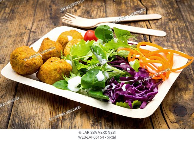 Falafel and salad on wooden disposable plates and cutlery