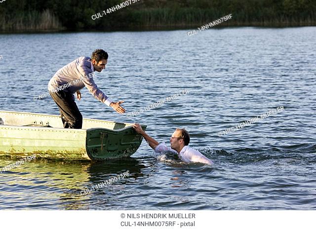 businessman helping man overboard