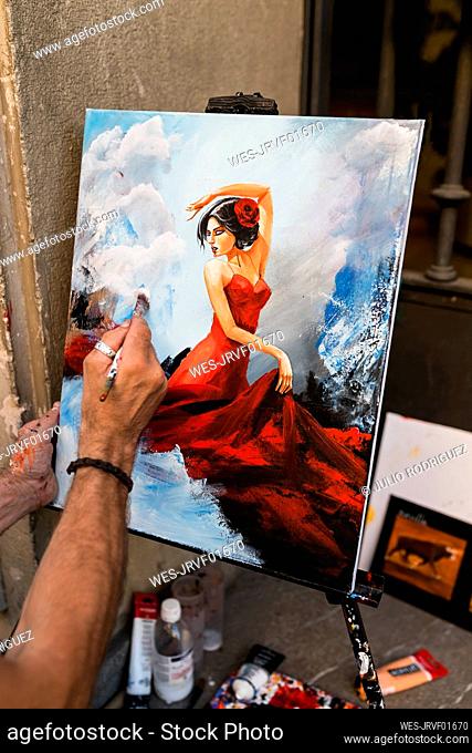 Creative male street artist painting female on canvas