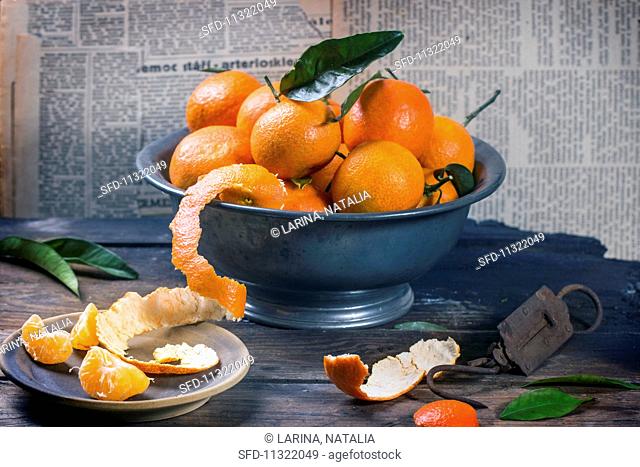 An arrangement of clementines in a metal bowl on a rustic wooden table