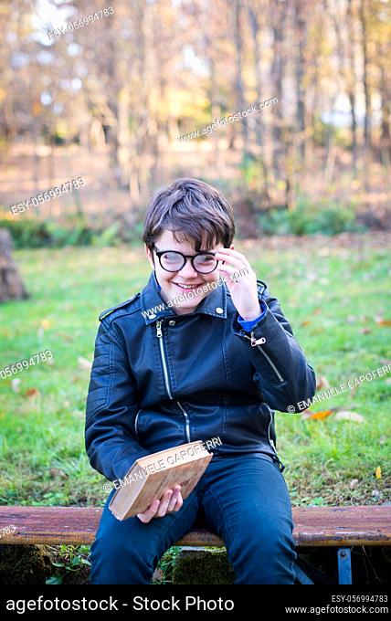 little boy with glasses and book in hand smiles -pleasure to read outdoors