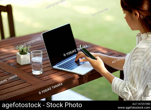 Japanese woman working with laptop in the garden