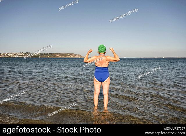 Woman flexing muscles amidst sea