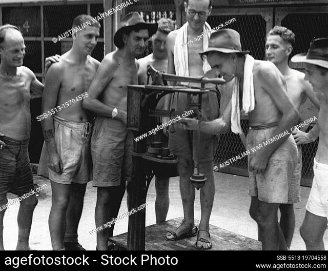 Members of 8 Division, ex prisoners of war of the Japanese, checking their weight gains on a set of scales in the jail courtyard. September 19, 1945