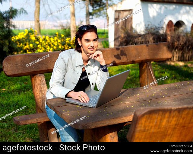 Young woman works on a laptop computer outdoor