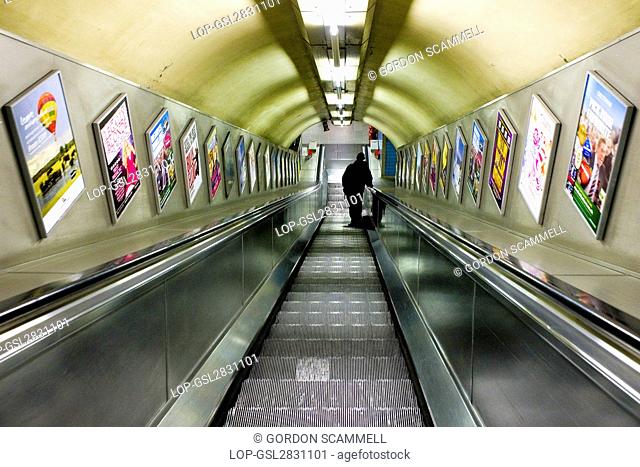 England, London. A man travelling down an escalator in a London Underground station