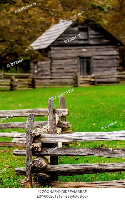 Beautiful Autumn scene showing rustic old log cabin surrounded by split rail fence