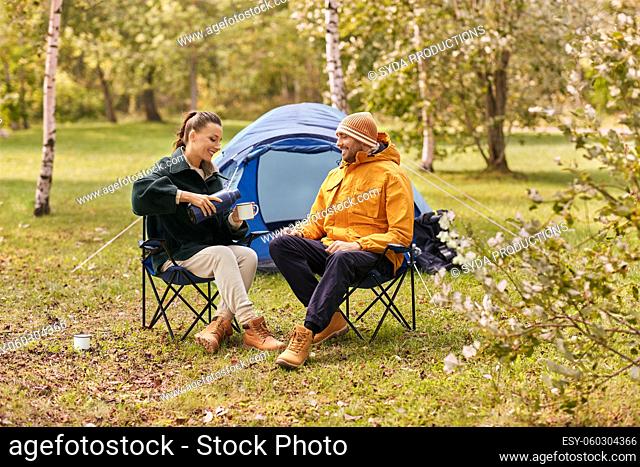 happy couple with thermos pouring tea at tent camp