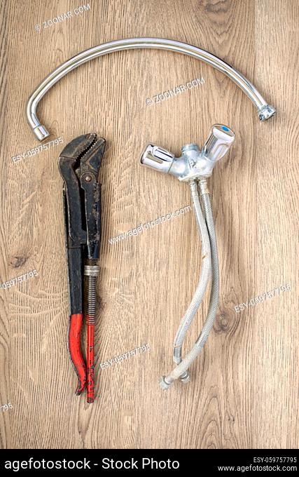 Rusty old plumbing wrench and tap on wooden background