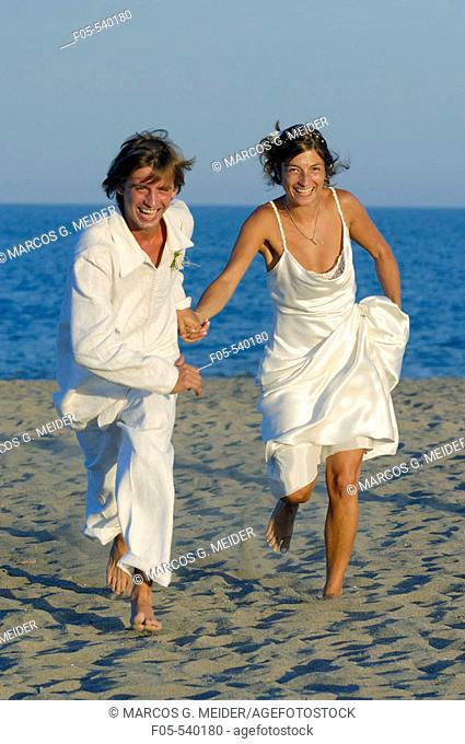 Newly young married couple running on the beach