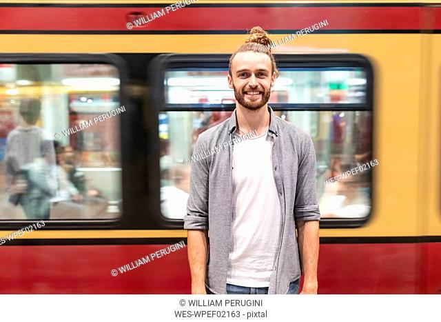 Young man at train station with blurred train as background
