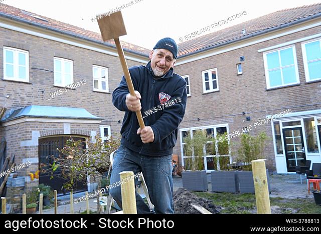senior man building fence in garden
