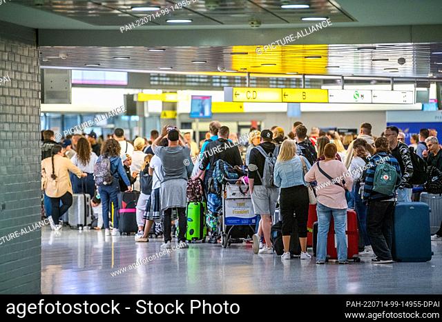 14 July 2022, Lower Saxony, Hanover: People wait at a check-in counter in the departure hall of Terminal A at Hannover Airport