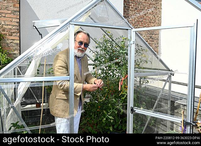 08 August 2022, Berlin: The musician and actor Friedrich Liechtenstein stands on the terrace of his apartment in a greenhouse where he has planted tomatoes
