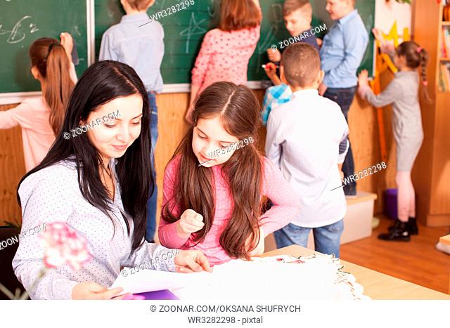 Young teacher helping schoolgirl in the classroom during a break
