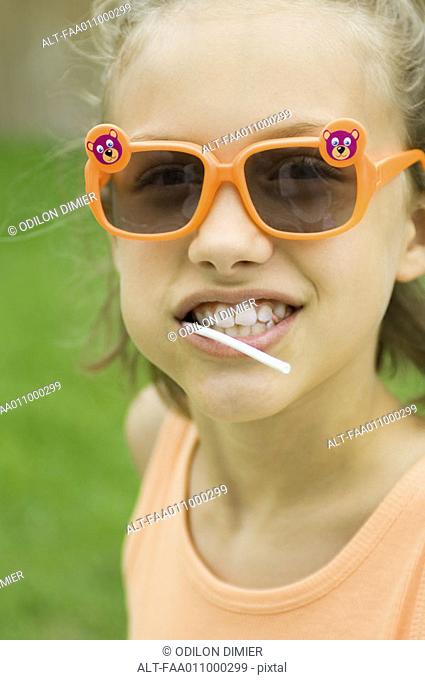 Girl wearing sunglasses, lollipop in mouth, portrait