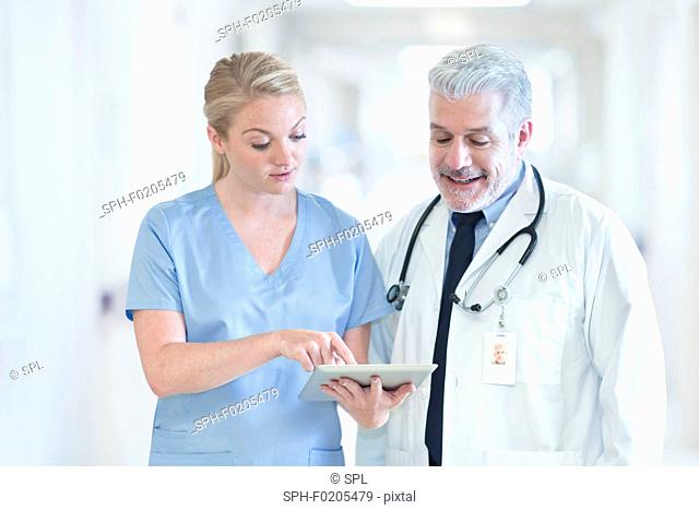 Mature doctor with colleague using tablet